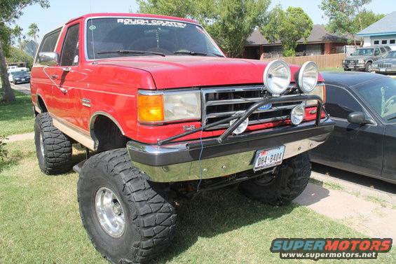 Red lifted 1990 Ford Bronco with off-road lights and "Rough Country" banner