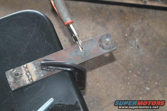 Metal bracket clamped and welded to black surface