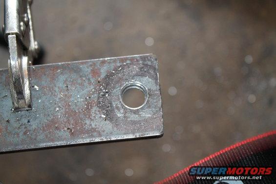 Metal bracket with a threaded hole, held by a clamp. Supermotors logo visible