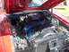 1970 Ford Ranchero - The engine bay of a red 1970 Ford Ranchero is shown with the hood open, revealing the V8 engine and surrounding components.