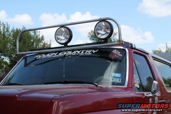 Red Ford Bronco with a light bar on top, has 'Rough Country' sticker on windshield
