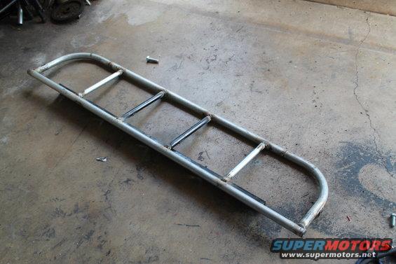 Metal light cage with curved ends and horizontal bars, lying on a concrete floor