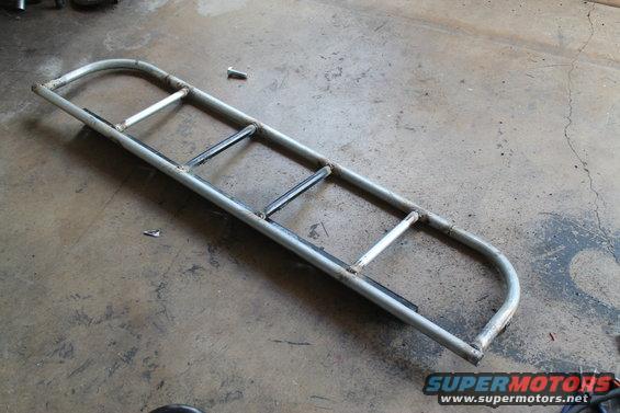 Custom metal light cage with multiple horizontal bars, lying on a concrete floor