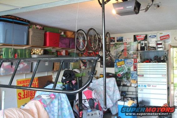 Garage interior with shelves full of bins, bicycles hanging, tool chest, and posters on the wall