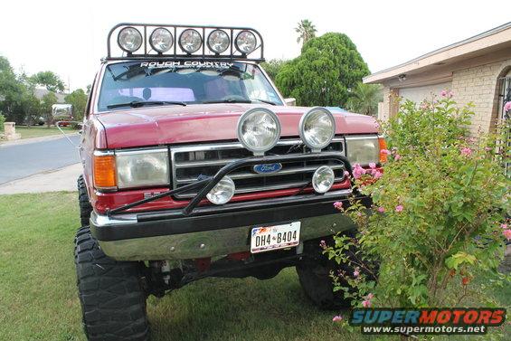 Red Ford Bronco with a light bar on the roof and off-road lights on the grille