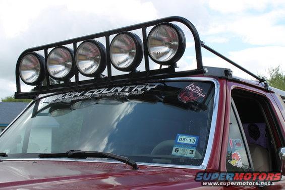 Red SUV with roof-mounted light bar and 'Rough Country' sticker