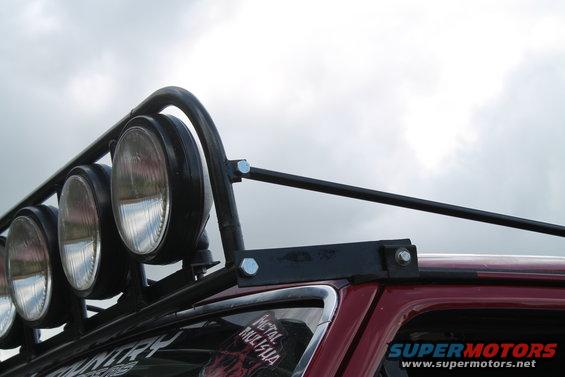 Close-up of a roof rack with multiple lights mounted on a red vehicle