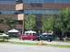 1970 Ford Ranchero - A gathering of people are seen near tents and vehicles in front of a modern office building.