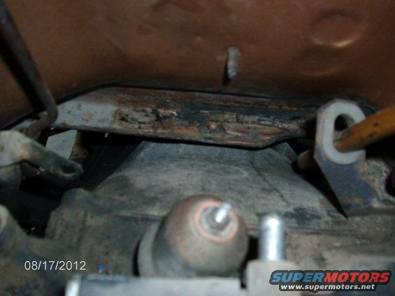 Underside of a vehicle showing rusty metal parts and some engine components