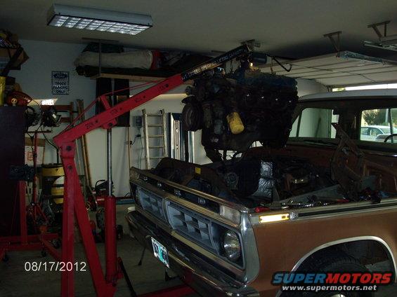 Brown truck with engine hoist removing the engine. Visible grille and headlights