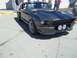 1970 Ford Ranchero - Dark gray 1967 Shelby GT500 Mustang parked on pavement with people in the background.