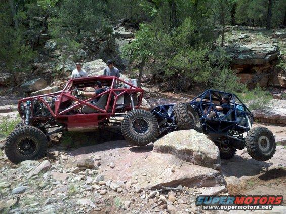 Red off-road buggy navigating rocky terrain next to a blue buggy
