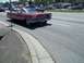1970 Ford Ranchero - A classic red convertible cruises down the road with other vehicles in the background.