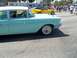 1970 Ford Ranchero - A classic aqua and white 1957 Chevrolet Bel Air sedan is seen from the side, with a modern yellow Corvette driving behind it.