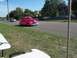 1970 Ford Ranchero - A vintage pink sedan cruises down the road on a sunny day.