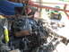 1966 Ford Ranchero - A vehicle's engine bay is being worked on, with a chain hoist overhead and a lawn tractor visible in the background.