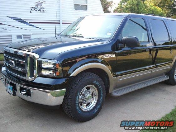 Black 2001 Ford Excursion parked in front of a white RV