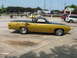 1972 Ford Ranchero - A yellow 1972 Ford Ranchero with a black hood and bed cover is parked in a lot.