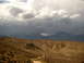 1996 Ford Bronco - A vast desert scene unfolds with arid terrain and imposing mountains beneath a dramatic, cloud-filled sky.