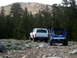 1996 Ford Bronco - Two off-road vehicles, a white 1996 Ford Bronco and a blue ATV, navigate a rocky mountain trail.