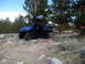 1996 Ford Bronco - Blue side-by-side ATV navigates a rough, rocky trail through a wooded mountain area.