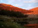 1996 Ford Bronco - A mountain landscape is illuminated by the warm glow of sunset, with trees and a lake in the foreground.