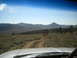 1996 Ford Bronco - Driving on a winding dirt road through a mountainous, arid terrain under a clear blue sky.