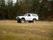 1996 Ford Bronco - Modified 1996 Ford Bronco sits in a dry, grassy field with a dense forest in the background.