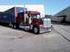 2003 Ford Crown Victoria - A maroon semi-truck is parked next to a blue shipping container in an industrial area.