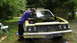 1973 Ford Torino - A man works on the engine of a 1973 Ford Torino, which has its hood open and is parked outdoors.