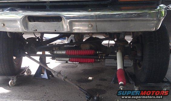 Front suspension components with red shock absorbers and chrome bumper above