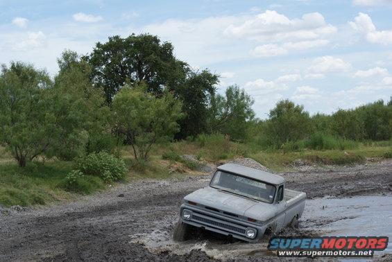 Gray 1965 Chevrolet C10 pickup truck driving through a muddy track
