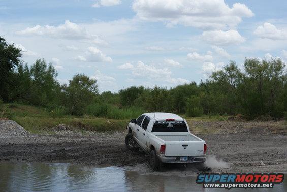 White pickup truck driving through mud and water. Text on rear window says 'WEEKEND 4 WHEELERS'