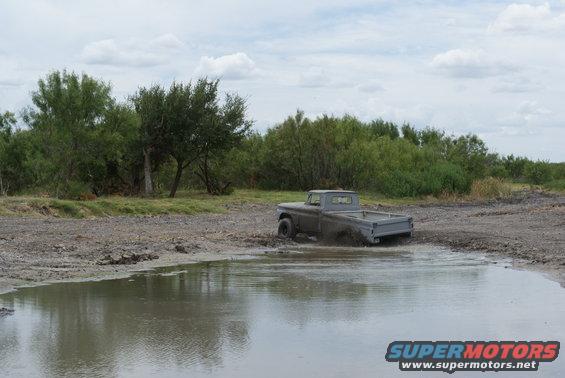 Gray pickup truck stuck in mud puddle, rear view