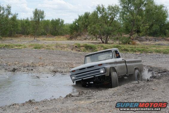 Gray 1964 Chevrolet C10 pickup truck navigating a muddy off-road path