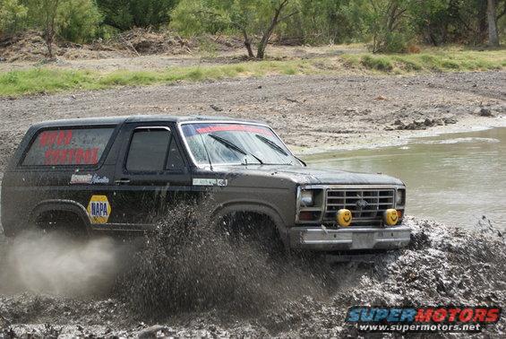 Black Ford Bronco driving through mud, with NAPA logo and red text on window