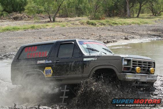 1989 Ford Bronco driving through mud, with "WOOD CONTROL" and NAPA logos on the side