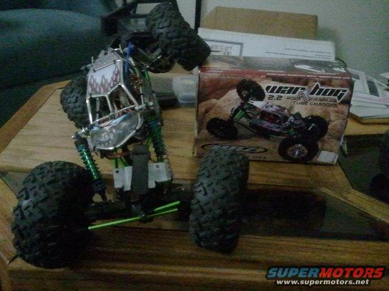 Remote control rock crawler toy with green shocks and a box labeled 'war hog 2.2 rock crawler tube chassis'