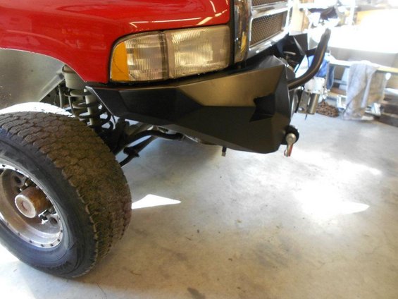 Close-up of a custom black front bumper and tire on a red truck, likely a Dodge Ram from the early 2000s