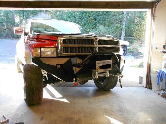 Red and white pickup truck front view with custom bumper, winch, and Washington license plate