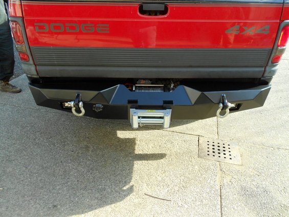 Red Dodge pickup truck rear with black aftermarket bumper and winch