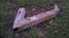 1989 Ford Bronco - A metal component, heavily coated in mud, lies on the ground amidst grass and dirt.