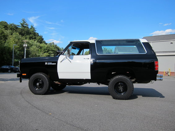 Black and white SUV with "RAMCHARGER" badge on fender, seen from the side