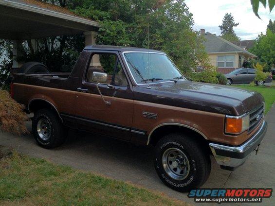 Brown and tan 1991 Ford Bronco parked on a driveway, spare tire visible in the bed