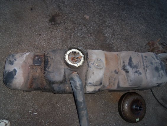 Used fuel tank with fuel pump assembly and a torque converter on the ground