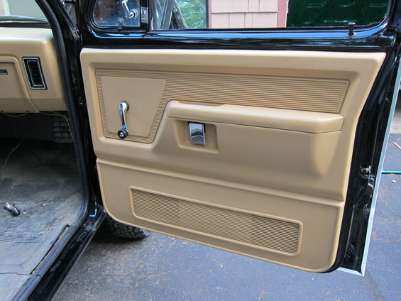 Tan door panel interior with window crank and chrome door handle. 1987 Dodge 1500