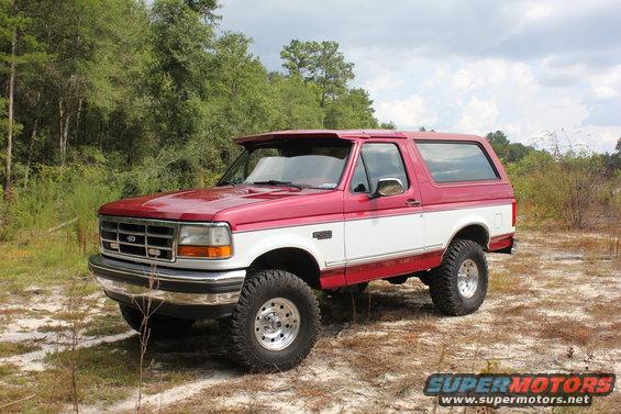 Red and white 1995 Ford Bronco with off-road tires parked outdoors