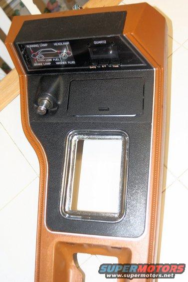 Brown and black dashboard trim with warning lights for running lamp, headlamp, low fuel, and brake lamp, plus a quartz clock