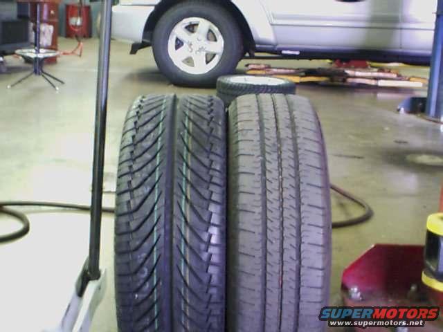 two tires in a garage, one is new and the other is used