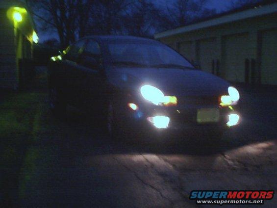 Front view of a dark sedan at night, headlights on